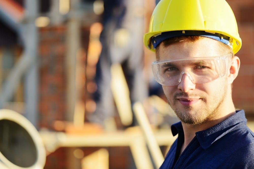 Male construction worker smiling at a building site-1